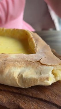 Kadınların elleri Adjarian Khachapuri 'den bir parça koparıp erimiş peynir ve yumurta sarısı karışımına batırıyor. Geleneksel Gürcü yemek kavramının tadını çıkarıyorum. khachapuri