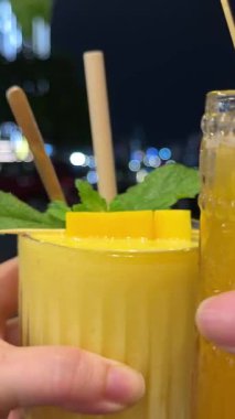 Yakın plan. Ellerinde buz küpleri olan iki alkollü kokteyl bar tezgahında gelin ve damat. Aşık cinsiyet çifti. Bir erkek ve kadın el ele tutuşup bardakları yanyana tutarlar. Düğün konsepti. Yüksek kalite