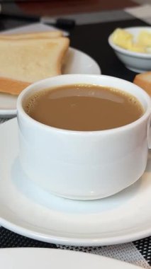 Restoranda kahvaltı. Taze hamur işleri, meyveler, omlet, tost, yoğurt ve ahşap masada bir fincan kahve. Otelde günaydın. Yüksek kalite 4k görüntü