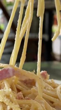 Lezzetli kremalı makarna Carbonara, İtalyan spagettisi ile dolu bir restoranda beyaz bir tabakta duruyor. Yüksek kalite 4k görüntü