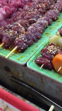 Sokak yemekleri şefi Gece Pazarı 'nda et, sebze ve ananas şişleri pişiriyor ve canlı Tayland gece yemeği kültürünü yakalıyor. Yerel yemek. Yüksek kalite 4k görüntü