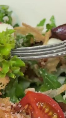 Çatalla Sezar salatası yemek. Tavuk fileto, marul, domates, bıldırcın yumurtası, kızarmış ekmek ve parmesan peynirinden yapılmış sağlıklı bir salata. Yüksek kalite 4k görüntü