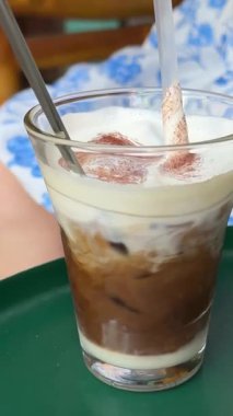 Beyaz elbiseli kız yazın soğuk içecekle kahveyi karıştırıyor beyaz elbiseli güzel bir kadın yaz kafesinde oturuyor. Yüksek kalite 4k görüntü