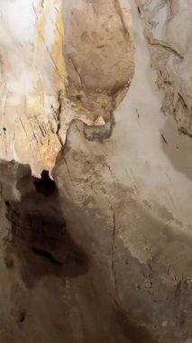 Okyanus dalgalarının engebeli kaya oluşumları ve mağaranın içini aydınlatan güneş ışığıyla volkanik bir deniz mağarasına çarpmasının dramatik bir görüntüsü. Yüksek kalite 4k görüntü