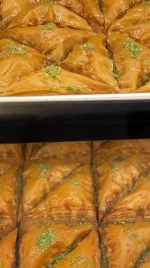 Kırsal tepside dinlenen altın katmanlı baklava geleneksel pastaların karmaşık katmanlarını ve profesyonel fırın ortamında parlayan şurubu sergiliyor. Yüksek kalite 4k görüntü
