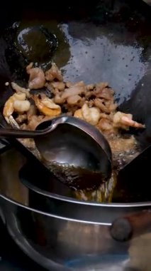 Profesyonel şef karidesleri siyah tavada pişirir ve restoran mutfağında zeytinyağı ile pişirir. Lezzetli deniz ürünleri pişirme teması. Akıllı telefonlar için dikey video, sosyal medyada tabletler. 