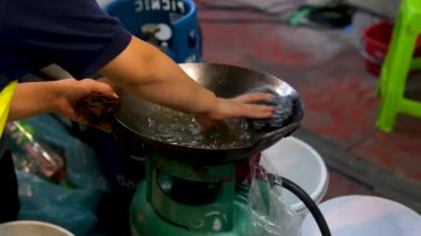 Kadın elektrikli sobanın yüzeyini sarı bir bez parçasıyla siliyor ve tava koyuyor. Modern mutfakta yemek pişirmek için iş yeri hazırlama kavramı. Tavayı paçavrayla yıka.