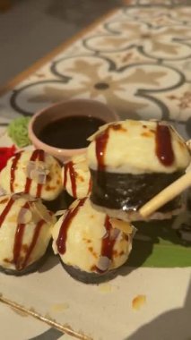 Suşi rulosunu krem peynir kapağıyla plastik tepsi kapağından ahşap çubuklarla alıyorum. Geleneksel Asya yemekleri. Sağlıklı doğu deniz ürünleri. Suşi peynirli rulo