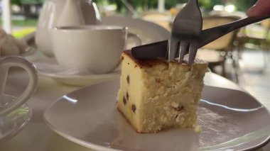 Pasta çatalı, süzme peynir güveci. Bir parçayı çatal-çatal-çay sokak kahvesi, peynirli keki kuru üzümle kesmiş. Yüksek kalite 4k görüntü