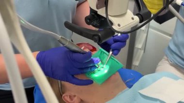 Diş hekimliğinde mikroskop altında diş bakımı yapan kauçuk bant ağıza girmez. Dişçideki kadın. Diş hekimliği mikroskobundaki en son pahalı ekipman..