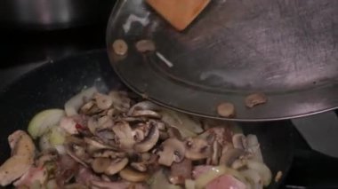 Ahşap bir mutfak spatulası taze çiğ et küpleri ve doğranmış soğanı siyah bir kızartma tavasında karıştırır. İçindekiler kaynayan yağın içinde cızırdıyor. Lezzetli bir yemek için aşçılık sürecinin kapanışı.