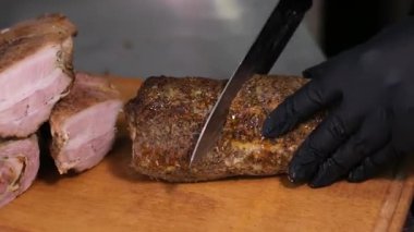Ahşap bir tahtanın üzerinde siyah lateks eldivenlerle et balyk ellerini keserek, et dilimleyerek, ev yapımı sigara içerek lezzetli bir et dilimleyerek. Yüksek kalite 4k görüntü