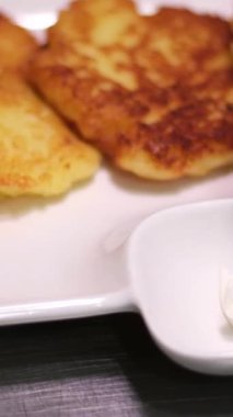 Patatesli gözleme servisi. Patatesli krepler tabakta görünür, ekşi krema koyar ve yeşil maydanoz ekler. Geleneksel Ukrayna mutfağı. Yüksek kalite 4k görüntü