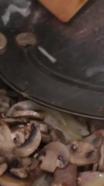 Ahşap bir mutfak spatulası taze çiğ et küpleri ve doğranmış soğanı siyah bir kızartma tavasında karıştırır. İçindekiler kaynayan yağın içinde cızırdıyor. Lezzetli bir yemek için aşçılık sürecinin kapanışı.