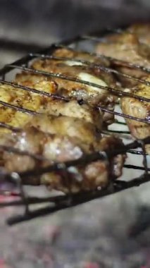 Tuz, baharat ve otlarla kızartılmış tavuk butları koyu beton bir arka planda. Izgarada tavuk budu ızgarası var. Demir ızgarayı çevir.