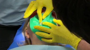 Diş hekimliğindeki kauçuk bant ağzına girmez. Dişçideki kadın. Diş hekimliği mikroskobundaki en son pahalı ekipman..