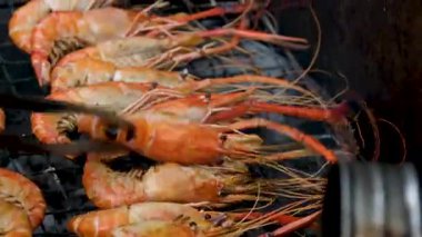 Şef ızgarada yağlı karides ve baharat pişiriyor. Yanan karidesler tavaya fırlatıyor. Dorado ve ızgarada somon balığı bifteği. Restoran yemeği konsepti. Deniz ürünleri barbeküsü. 