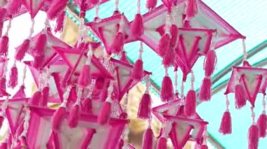 Çok sayıda rengarenk origami kağıt vinç zarif bir şekilde pencerenin yanında asılı, parlak bir gökyüzü ve arka planda bulanık şehir binaları ve ağaçlarıyla birlikte. Yüksek kalite 4k görüntü