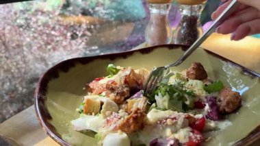 Kadın masada otururken Sezar salatası, parmesan peyniri, marul ve vişneli domates yiyor. Yüksek kalite 4k görüntü