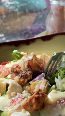 Kadın masada otururken Sezar salatası, parmesan peyniri, marul ve vişneli domates yiyor. Yüksek kalite 4k görüntü