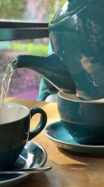 cozy restaurant woman pours tea In emerald green cup autumn Cold Warmth Comfort couples drinking tea wooden table. High quality 4k footage