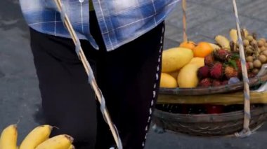 Hoi 'nin geleneksel meyve satıcıları Vietnam' da omuz direkli sepetler taşıyarak tropikal meyveler satarak otantik kültür ve günlük piyasa yaşamını gösteriyorlar.