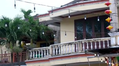 Geleneksel Hoi An binasının ön cephesi ikonik sarı duvarları, kemerli balkonları ve renkli fener gösterimiyle kasabaların mimari cazibesini sergiliyor. Yüksek kalite 4k görüntü