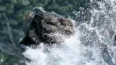 Dev bir güç dalgası günbatımında gökyüzü arka planına çarpıyor. Madeira kıyısına vuran fırtınalı okyanus sörfü ağır çekim, Porto Moniz. Yüksek kalite 4k görüntü