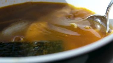 Bir kase ev yapımı tavuk çorbası haşlanmış yumurta, sebze ve taze otlar. Bir kaşık kasenin içinde duruyor. Kaynamış yumurtayla birlikte bambu hasırında servis edilen doyurucu ve sağlıklı bir yemek. Diyet tavuk çorbası..