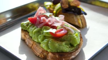Şef taze yeşillikler, mantarlar ve baharatlarla süslenmiş lezzetli bir avokado tostu sunarak sağlıklı ve görsel olarak çekici içerikleri vurguluyor. Yüksek kalite 4k görüntü