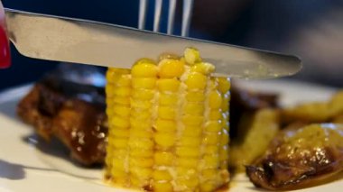 Koçandan mısır tanelerini bıçakla metal bir kaseye kesen elleri gösteren bir sahne. Yüksek kalite 4k görüntü