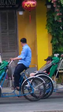 Hoi 'deki turistler geleneksel tribünlere binmiş Vietnam' da tarihi eski şehir sokaklarında kültürel mirasın, canlı atmosferin ve otantik Asya yaşam tarzının tadını çıkarıyorlar.