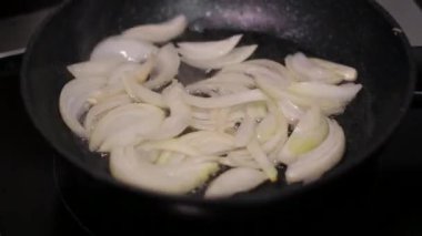 Doğranmış soğanlar sebze yağında tavada kızartılır, ara sıra karıştırılır. Yakın plan. Yüksek kalite 4k görüntü