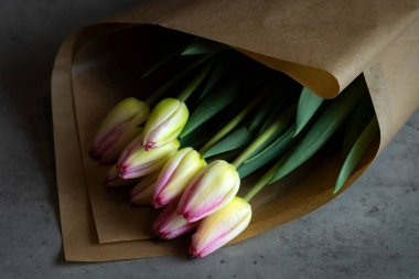 Siyah arka planda bir kese kağıtta beyaz laleler. bahar konsepti.