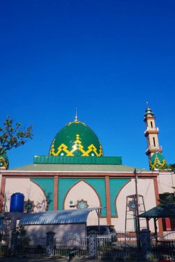 Caminin ihtişamı ve mavi gökyüzünün altında yükselen minaresi çarpıcı bir manzara yaratıyor.