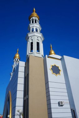 Caminin ihtişamı ve mavi gökyüzünün altında yükselen minaresi çarpıcı bir manzara yaratıyor.