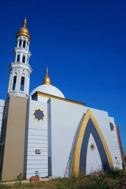Caminin ihtişamı ve mavi gökyüzünün altında yükselen minaresi çarpıcı bir manzara yaratıyor.