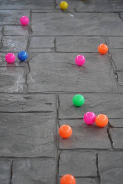 Beton zeminde küçük renkli toplar, genellikle çocuklar tarafından oynamak için kullanılır.