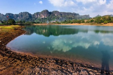 Manzara berrak su, dağlar ve ağaçlarla dolu bir göldür.