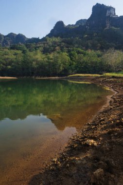 Manzara berrak su, dağlar ve ağaçlarla dolu bir göldür.