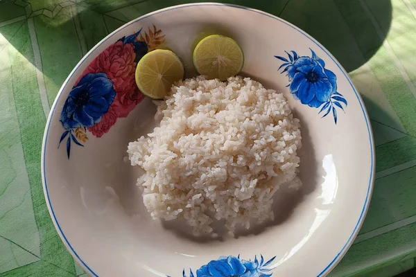 White rice is plated on a white plate on the dining table ready to be eaten
