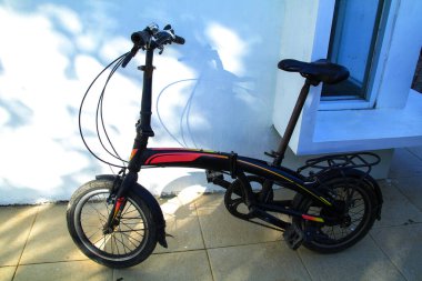 Evin terasına siyah katlanmış bir bisiklet park edilmiştir.