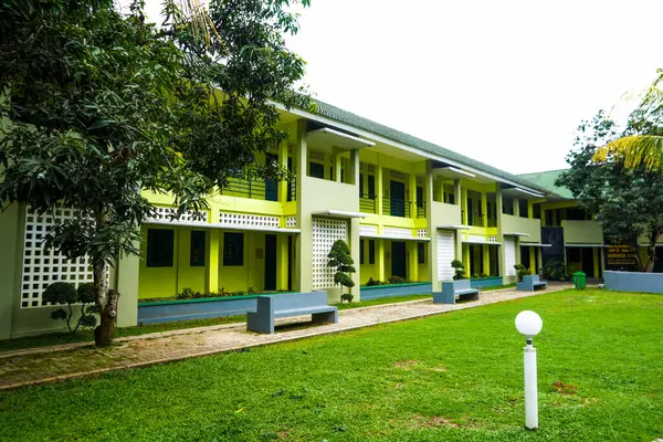 The school building is green and friends with green grass
