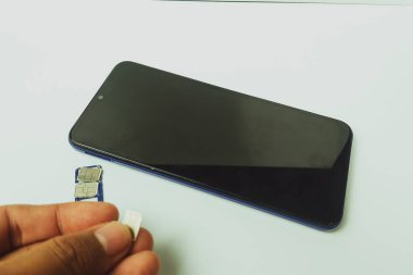 Kapalı alandaki düz beyaz masada cep telefonu ve kartlar.