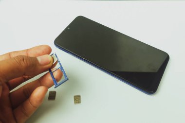 Kapalı alandaki düz beyaz masada cep telefonu ve kartlar.