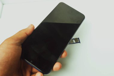 Kapalı alandaki düz beyaz masada cep telefonu ve kartlar.