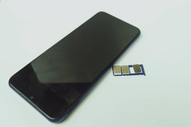 Kapalı alandaki düz beyaz masada cep telefonu ve kartlar.