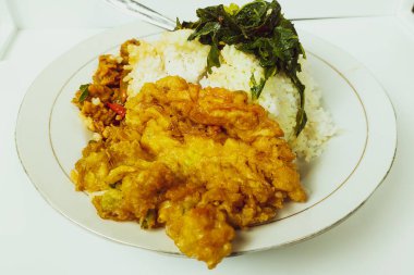 Masadaki beyaz tabakta pilav ve omlet karışımı.