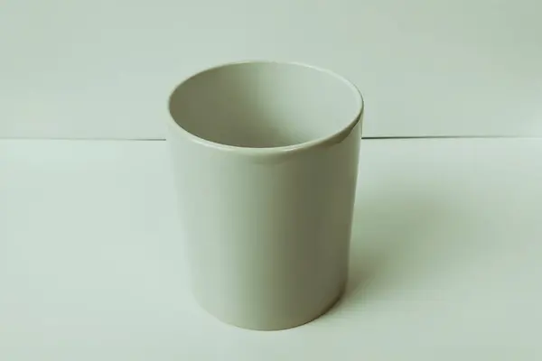 Plain white mug on a white table, photo suitable for mockup example.