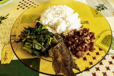 Tabakta hazır pilav ve meze tabakları, arka planda pirinç tarlalarının fotoğrafı.